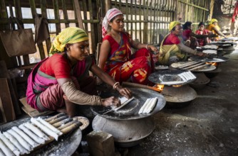 Women prepare 'Pitha', Assamese traditional rice-based sweets or snacks, as part of preparations