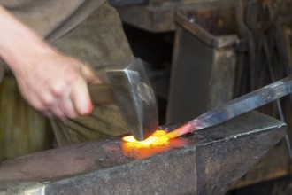 Sparks spray, a blacksmith forging, working at the Ehnert forge in Dresden-Bühlau, Saxony, Germany