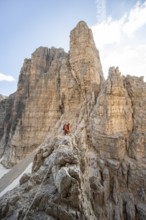 Mountaineer climbs an exposed rock in the secured Via Ferrata Bocciere Centrale via ferrata,