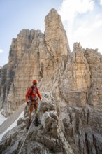 Mountaineer climbs on an exposed rock in the secured Via Ferrata Bocciere Centrale via ferrata,