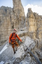Mountaineer climbs on an exposed rock in the secured via ferrata Bocciere Centrale, Brenta