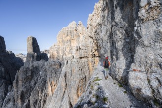 Mountaineers on an exposed rock band in the secured Via Ferrata Bocciere Centrale via ferrata,