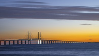 Modern Øresund bridge across the sea at sunset with colorful sky illuminated by a colorful sunset,