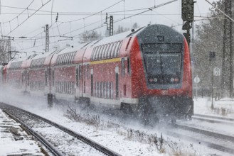 RegionalExpress RE on the road through a winter landscape in snowfall. A train on the line in the