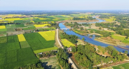 An aerial view reveals a gently curving river winding through the countryside, its silvery surface