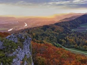 View of an autumnal forest from the Gisliflue, behind the Jurassic foothills in the light of the