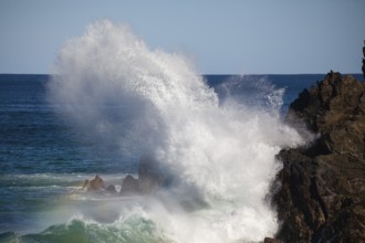 Waves crash against rocks at the mainland's easternmost point, creating rainbows in the ocean spray