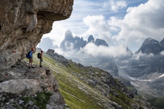 Two mountaineers on a path in front of a picturesque mountain landscape with rocky peaks, Via