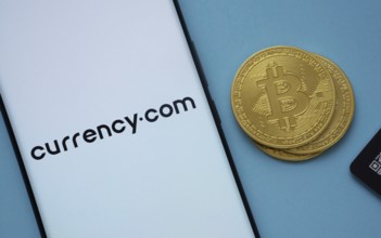 Dhaka, Bangladesh- 22 June 2025: Currency.com logo on smartphone screen near Bitcoin coin and QR