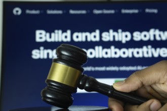 Dhaka, Bangladesh- 20 June 2025: A hand holds a gavel in front of a computer screen displaying