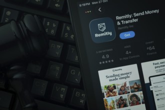 Dhaka, Bangladesh- 28 Oct 2025: An iPad displaying the Remitly app against a judge's gavel and dark