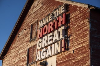 Red fishing building with the inscription Make the North great again at Vardö harbour, Vardø,