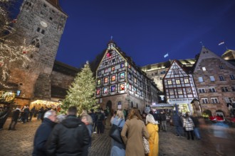 Christmassy illuminated square with the historic Pilate House with advent calendar, in the evening