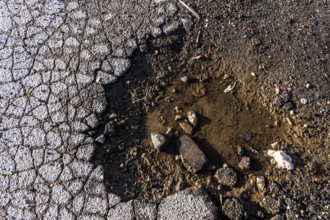 Pothole, asphalt surface, floor, with many small cracks, roadway, parking lot