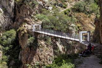 White bridge over a rocky gorge with people in shade, The landscape of the Colca Canyon in the