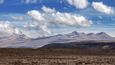 Barren landscape with mountains in the background and scattered clouds in the sky, The highlands of