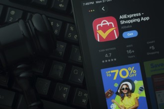 Dhaka, Bangladesh- 21 Nov 2025: An iPad displaying the AliExpress app against a judge's gavel and