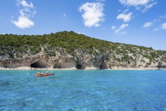 Kayakers in clear blue water, picturesque rocky coast, cliffs and Cala Luna beach, Golfo di Orosei,