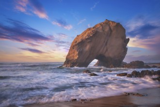 Penedo do Guincho, a large boulder rock arch at Praia da Santa Cruz, Portugal, with ocean waves and