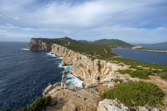 Tourist enjoying the view of steep cliffs by the sea, coastal landscape, cliffs on the Capo Caccia
