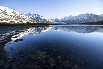 Mountain peaks with Portage Glacier glacier and snow reflected in Divide Lake mountain lake in