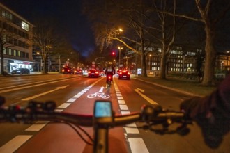 Cycling in the city, in the dark, in the evening, cycling on a bike lane, marked in red,