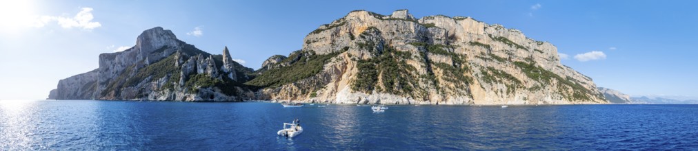 Couple on motorboat off picturesque rocky coast, cliffs with L'Aguglia pinnacle, blue sea and Cala