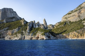 Picturesque rocky coast, cliffs with caves in the morning light, L'Aguglia rock peak, blue sea and
