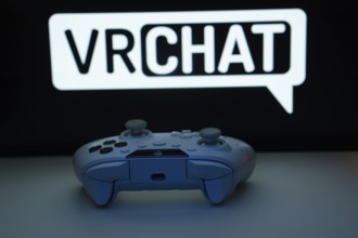 Dhaka, Bangladesh- 14 Nov 2025: A close-up of a white gamepad with the VRChat seen on screen in the