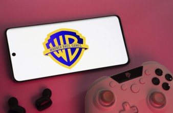 Dhaka, Bangladesh- 22 Mar 2025: Smartphone with Warner Bros. Games logo, game controller, and