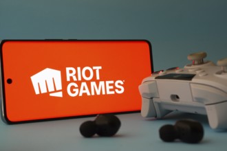 Dhaka, Bangladesh- 23 Mar 2025: A smartphone with a Riot games icon next to a controller and