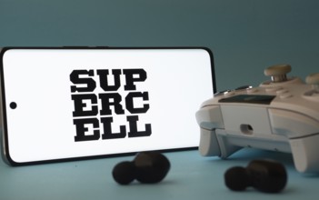 Dhaka, Bangladesh- 23 Mar 2025: A smartphone with a Supercell icon next to a controller and earbuds