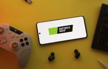 Dhaka, Bangladesh- 23 Mar 2025: Smartphone with Geforce Now logo, game controller, and earbuds on a