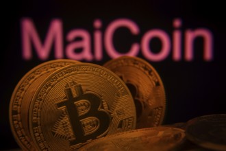 Dhaka, Bangladesh- 03 Sep 2025: Close-up of Bitcoin coins with the MaiCoin logo visible on a screen