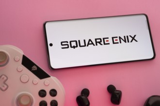 Dhaka, Bangladesh- 22 Mar 2025: Smartphone with Square Enix logo, game controller, and earbuds on a