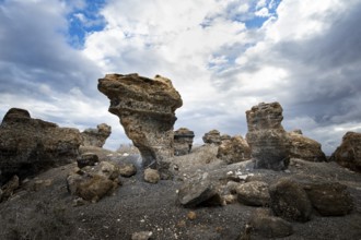 Eroded rock formations in volcanic landscape with dramatic cloudy skies, Ciudad Estratificada or