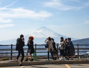 Tourists enjoy the view and take pictures, view of the snow-covered summit of Mount Fuji volcano in