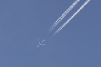 Boeing 747 jumbo jet cargo aircraft flying in a blue sky with contrails or vapour trails behind,