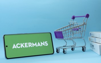 Dhaka, Bangladesh- 03 July 2025: Smartphone with Ackermans logo next to a small shopping cart and