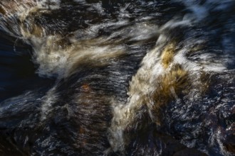 Stream flow with dark water, reflections and turbulences, long exposure, Sweden