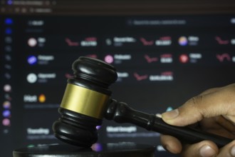 Dhaka, Bangladesh- 20 June 2025: A hand holds a gavel in front of a computer screen displaying