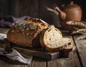 Rustic loaf of whole grain bread, fresh baked, close up of bread on dark wooden table, golden rust,