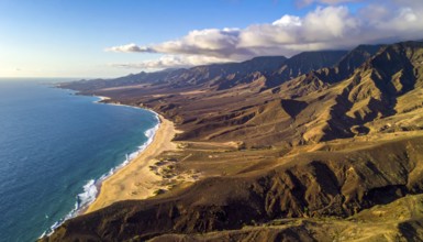 Desert landscape converges with ocean along a rugged coastal area, shore break at cliffs, blue