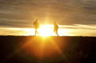 Woman and child walk across a dike on the island of Fehmarn at sunset, 13.10.2025, Fehmarn,