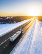 Petrol cargo truck lorry tanker driving on highway hauling oil products at sunrise, wide snowy