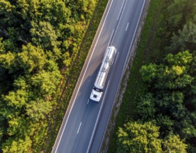 Petrol cargo truck lorry tanker driving on highway hauling oil products at sunrise, wide hilly