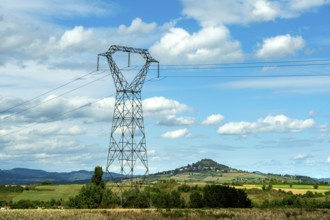 High voltage power lines against a bright blue sky with scattered clouds, Puy de Dome, Auvergne