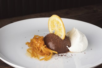 Chocolate mousse dessert with candied orange peel, dried orange slice, and cream on a white plate