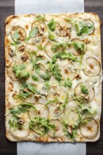 Gourmet flatbread preparing with pear, gorgonzola cheese, walnuts, and fresh arugula