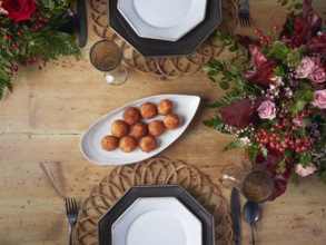 Crispy croquettes on an elegant white serving platter at a decorated dinner table